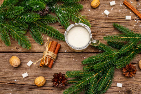 Christmas eggnog liqueur or cola de mono cocktail. Classical winter drink in glass mug, xmas decorations. Evergreen branches, cinnamon, walnuts, sugar. Old wooden background, top viewの写真素材