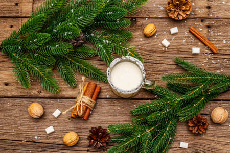 Christmas eggnog liqueur or cola de mono cocktail. Classical winter drink in glass mug, xmas decorations. Evergreen branches, cinnamon, walnuts, sugar. Old wooden background, top viewの写真素材