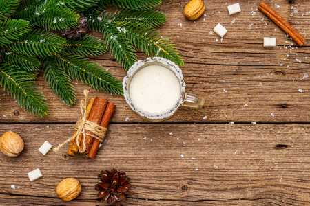 Christmas eggnog liqueur or cola de mono cocktail. Classical winter drink in glass mug, xmas decorations. Evergreen branches, cinnamon, walnuts, sugar. Old wooden background, copy space, top viewの写真素材
