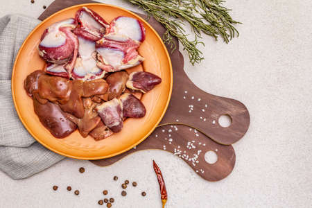 Fresh raw duck offal: heart, liver, stomach. Dry spices, salt, chili pepper. Wooden cutting boards, stone concrete background, copy space, top view, close upの写真素材