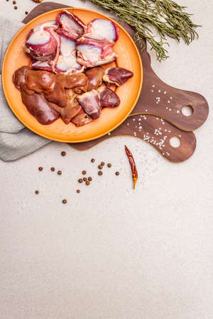 Fresh raw duck offal: heart, liver, stomach. Dry spices, salt, chili pepper. Wooden cutting boards, stone concrete background, copy space, top viewの写真素材