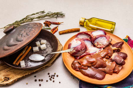 Fresh raw duck offal: heart, liver, stomach. Dry spices, salt, sugar, oil. Frying pan, stone concrete background, close upの写真素材