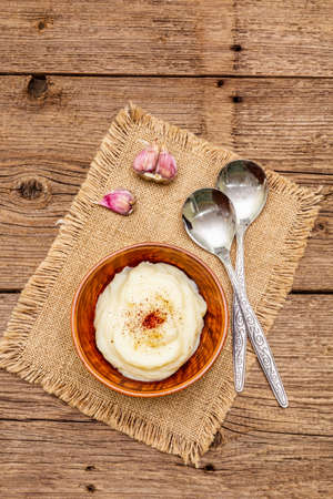 Homemade Thanksgiving garlic mashed potatoes with salt and pepper. Sackcloth napkin, spoons, old wooden boards background, copy space, top viewの写真素材
