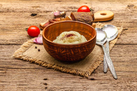 Homemade Thanksgiving garlic mashed potatoes with fresh tomatoes and pastrami. Sackcloth napkin, spoons, old wooden boards background, close upの写真素材