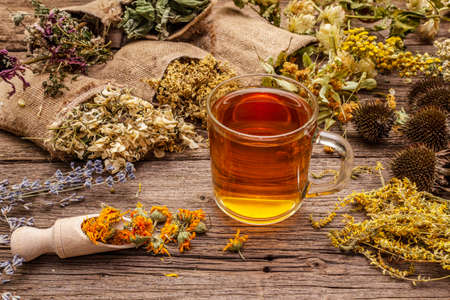 Tea with honey. Herbal harvest collection and bouquets of wild herbs. Alternative medicine. Natural pharmacy, self-care concept. Old wooden boards backgroundの写真素材