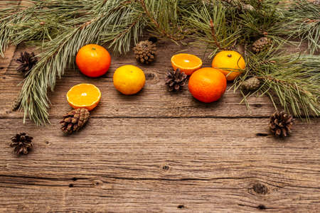 Spirit Christmas background. Fresh oranges, tangerines, pine branches and cones. Nature decorations, vintage wooden boards, flat lay, copy spaceの写真素材