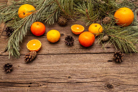Spirit Christmas background. Fresh oranges, tangerines, pine branches and cones. Nature decorations, vintage wooden boards, flat lay, copy spaceの写真素材