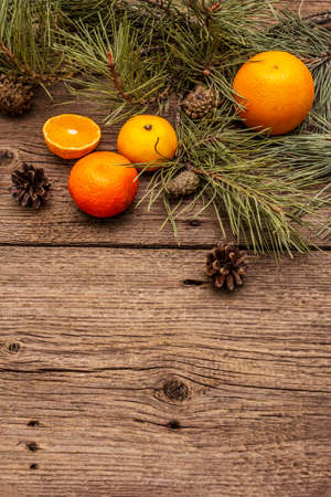 Spirit Christmas background. Fresh oranges, tangerines, pine branches and cones. Nature decorations, vintage wooden boards, flat lay, copy spaceの写真素材