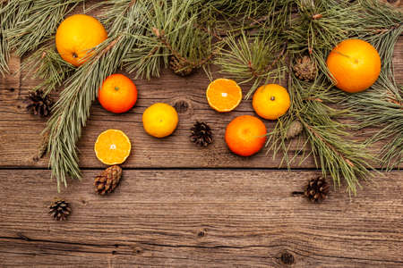 Spirit Christmas background. Fresh oranges, tangerines, pine branches and cones. Nature decorations, vintage wooden boards, flat lay, copy space, top viewの写真素材