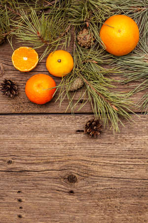 Spirit Christmas background. Fresh oranges, tangerines, pine branches and cones. Nature decorations, vintage wooden boards, flat lay, copy space, top viewの写真素材