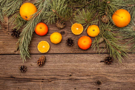Spirit Christmas background. Fresh oranges, tangerines, pine branches and cones. Nature decorations, vintage wooden boards, flat lay, copy space, top viewの写真素材