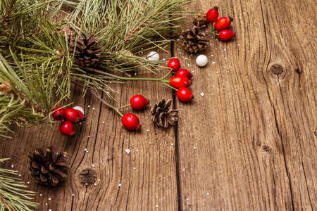 Spirit Christmas background. Fresh dog-rose berries, candies, pine branches and cones, artificial snow. Nature decorations, vintage wooden boards, flat lay, copy spaceの写真素材