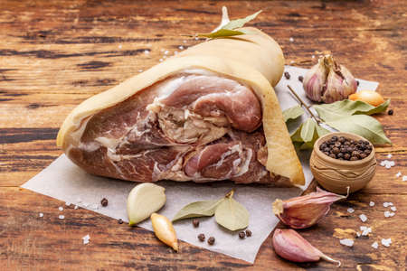 Raw pork meat - hock, knuckle or leg. Traditional ingredient for eisbein. Fresh meat, dry spices and vegetables. Old wooden table, rustic style, close upの写真素材