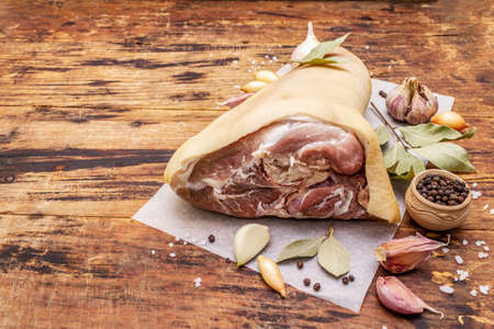 Raw pork meat - hock, knuckle or leg. Traditional ingredient for eisbein. Fresh meat, dry spices and vegetables. Old wooden table, rustic style, copy spaceの写真素材