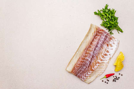 Raw pollock (Pollachius virens) fillet. Fresh fish for healthy food lifestyle. Lemon, parsley, sea salt, chili, black peppercorn. Stone concrete background, copy space, top viewの写真素材