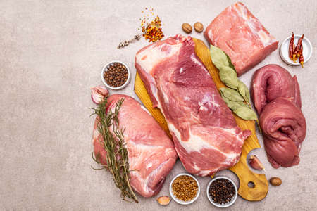 Assorted various fresh pork cuts. Raw meat with spices. Tenderloin, shoulder blade, neck, hind leg steak. Stone concrete background, top view, copy spaceの写真素材