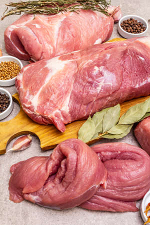 Assorted various fresh pork cuts. Raw meat with spices. Tenderloin, shoulder blade, neck, hind leg steak. Stone concrete background, close upの写真素材