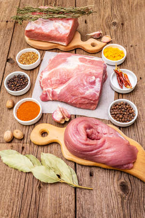 Assorted various fresh pork cuts. Raw meat with spices. Tenderloin, shoulder blade, neck. Old wooden boards backgroundの写真素材
