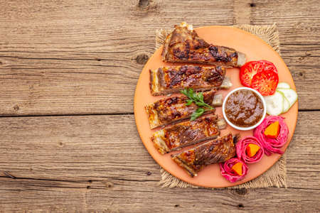 BBQ pork ribs with fermented, baked and fresh vegetables. Teriyaki sauce, spices, plum chutney. Old wooden boards background, copy space, top viewの写真素材