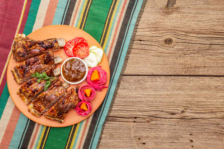BBQ pork ribs with fermented, baked and fresh vegetables. Teriyaki sauce, spices, plum chutney. Old wooden boards background, copy space, top viewの写真素材