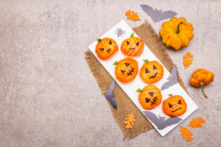 Funny Halloween Sushi Pumpkins Jack o Lantern, Sushi Monsters. Temari sushi, sushi balls. Healthy food for kids. Bats, leaves, stone concrete background, top view, copy spaceの写真素材