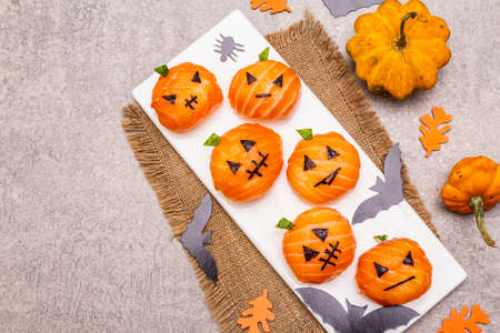 Funny Halloween Sushi Pumpkins Jack o Lantern, Sushi Monsters. Temari sushi, sushi balls. Healthy food for kids. Bats, leaves, stone concrete background, top viewの写真素材
