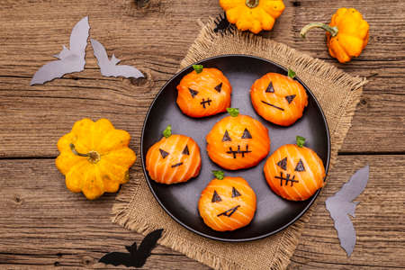 Funny Halloween Sushi Pumpkins Jack o Lantern, Sushi Monsters. Temari sushi, sushi balls. Healthy food for kids. Bats, napkin, old wooden boards background, top viewの写真素材