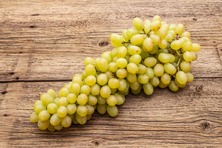 Bunch of sweet green seedless grapes variety "Kishmish". Ripe fruits autumn harvest. Healthy food concept. Old wooden boards background, copy space, close upの写真素材
