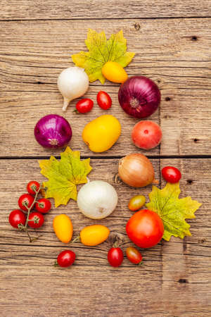 Autumn harvest vegetables cooking background. Assortment of different types onions and tomatoes. Old vintage wooden boards background, top view, close upの写真素材