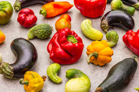 Trendy ugly organic vegetables. Assortment of fresh pepper, eggplant, cucumber, tomato, pumpkin. Cooking ugly food concept. Stone concrete backgroundの写真素材