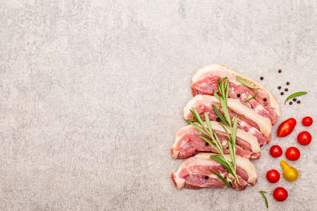 Raw pork belly with rind, peritoneum meat. Fresh tomato cherry, rosemary, spice. Ingredient for cooking healthy meal, animal proteins. Light stone concrete background copy space top viewの写真素材