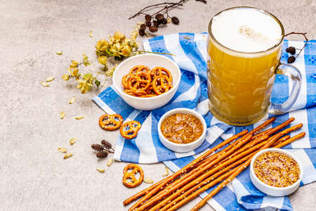 Oktoberfest set. Light beer, pretzels, mustard, sesame straw, hop. Traditional German cuisine, festival food. Bottles, linen napkin, stone concrete background, wooden backdrop copy spaceの写真素材
