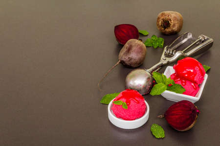 Beet ice cream, sorbet, gelato, sweet icing. Summer healthy refreshment dessert. Vegetarian (vegan) trendy food concept. With fresh vegetables and mint. Stone concrete background, copy spaceの写真素材