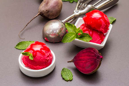 Beet ice cream, sorbet, gelato, sweet icing. Summer healthy refreshment dessert. Vegetarian (vegan) trendy food concept. With fresh vegetables and mint. Stone concrete background, close upの写真素材
