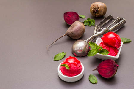 Beet ice cream, sorbet, gelato, sweet icing. Summer healthy refreshment dessert. Vegetarian (vegan) trendy food concept. With fresh vegetables and mint. Stone concrete background, copy spaceの写真素材