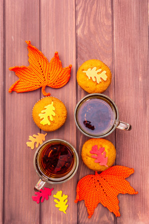 Hot autumn drink. Black tea with cupcakes, colorful leaves. Warm and comfortable mood concept....