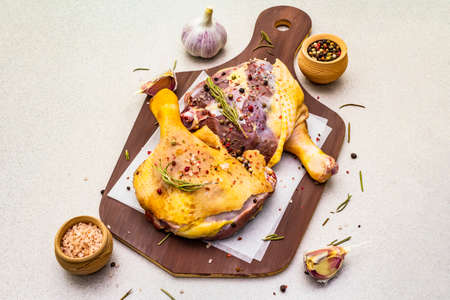 Raw duck legs. Fresh BIO ingredient for preparation traditional French confit. Spice, vegetable, herbs. Animal proteins and healthy fats, wooden board, stone background copy space, close upの写真素材
