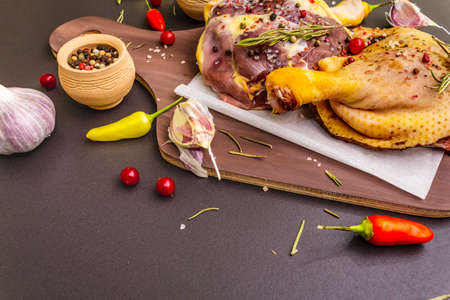 Raw duck legs. Fresh BIO ingredient for preparation traditional French confit. Spice, vegetable, herbs. Animal proteins and healthy fats, wooden board, stone background copy spaceの写真素材