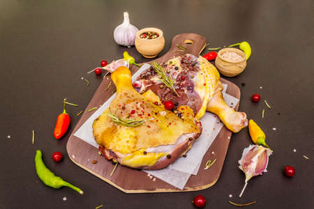 Raw duck legs. Fresh BIO ingredient for preparation traditional French confit. Spice, vegetable, herbs. Animal proteins and healthy fats, wooden board, stone background copy spaceの写真素材