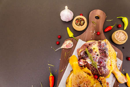 Raw duck legs. Fresh BIO ingredient for preparation traditional French confit. Spice, vegetable, herbs. Animal proteins and healthy fats, wooden board, stone background copy space top viewの写真素材