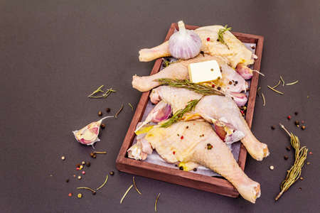 Raw chicken legs. Fresh BIO ingredient for preparation traditional food. Spice, vegetable, herbs, butter. Animal proteins and healthy fats, wooden box, stone background copy spaceの写真素材