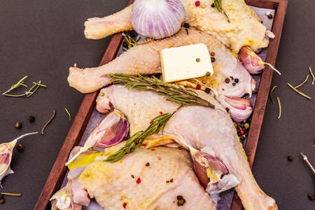Raw chicken legs. Fresh BIO ingredient for preparation traditional food. Spice, vegetable, herbs, butter. Animal proteins and healthy fats, wooden box, stone background top view close upの写真素材