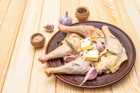 Raw chicken legs. Fresh BIO ingredient for preparation traditional food. Spice, vegetable, herbs, butter. Animal proteins and healthy fats, ceramic plate, wooden background copy spaceの写真素材