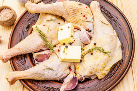 Raw chicken legs. Fresh BIO ingredient for preparation traditional food. Spice, vegetable, herbs, butter. Animal proteins and healthy fats, ceramic plate, wooden background top view close upの写真素材