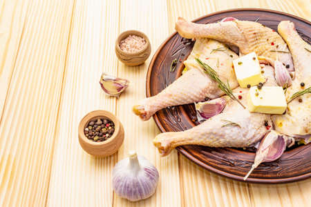 Raw chicken legs. Fresh BIO ingredient for preparation traditional food. Spice, vegetable, herbs, butter. Animal proteins and healthy fats, ceramic plate, wooden background copy spaceの写真素材