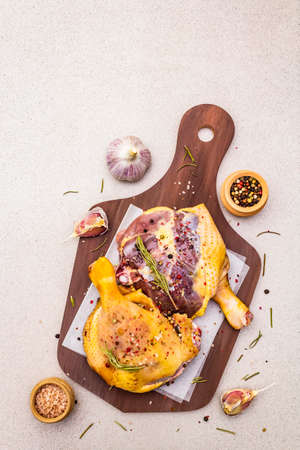 Raw duck legs. Fresh BIO ingredient for preparation traditional French confit. Spice, vegetable, herbs. Animal proteins and healthy fats, wooden board, stone background copy space, top viewの写真素材