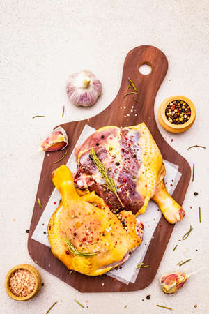Raw duck legs. Fresh BIO ingredient for preparation traditional French confit. Spice, vegetable, herbs. Animal proteins and healthy fats, wooden board, stone background, top view, close upの写真素材
