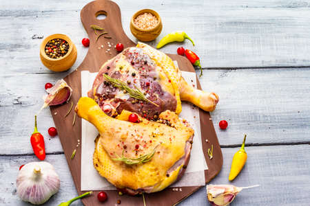 Raw duck legs. Fresh BIO ingredient for preparation traditional French confit. Spice, vegetable, herbs. Animal proteins and healthy fats, cutting board, wooden background copy space, top viewの写真素材