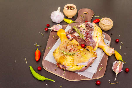 Raw duck legs. Fresh BIO ingredient for preparation traditional French confit. Spice, vegetable, herbs. Animal proteins and healthy fats, wooden board, stone background copy space close upの写真素材