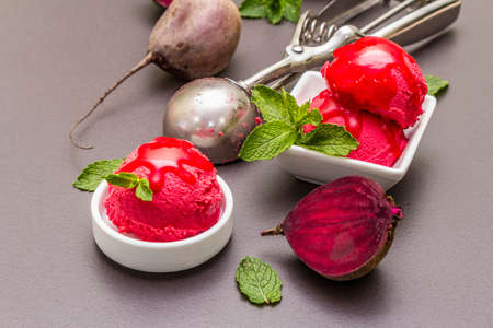 Beet ice cream, sorbet, gelato, sweet icing. Summer healthy refreshment dessert. Vegetarian (vegan) trendy food concept. With fresh vegetables and mint. Stone concrete background, close upの写真素材